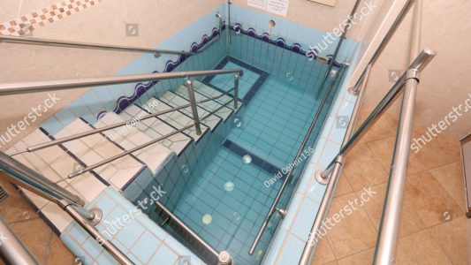 stock-photo-ritual-bath-used-for-spiritual-purification-blessing-on-the-wall-in-hebrew-translates-blessed-are-1121605370