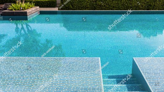 stock-photo-swimming-pool-made-by-mosaic-tiles-with-small-stairs-inside-the-clear-blue-water-which-not-moving-455276350
